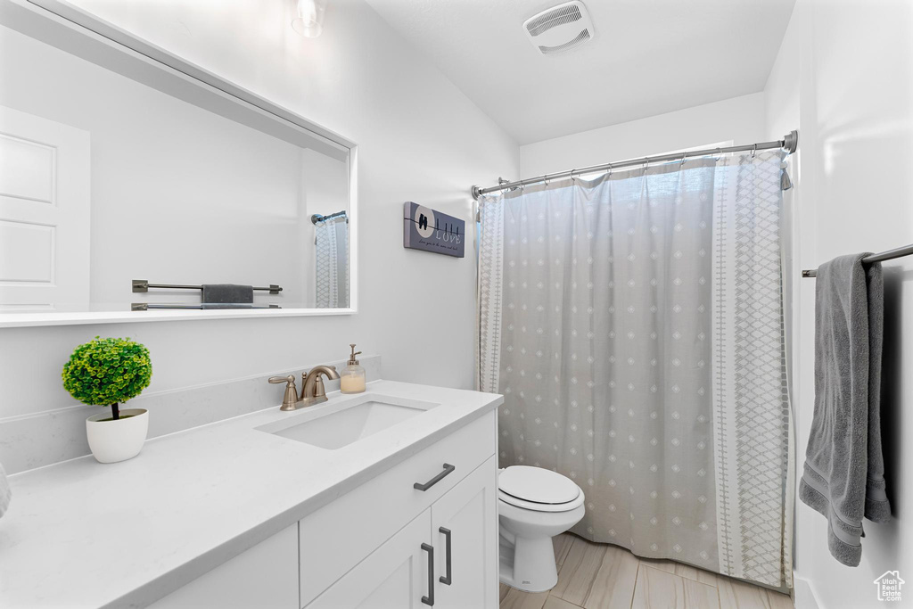 Bathroom with toilet, vanity, curtained shower, and vaulted ceiling