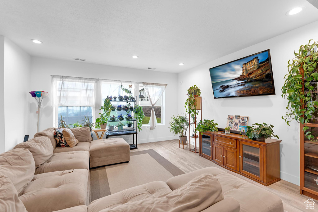 Living area with light wood-style flooring, baseboards, and recessed lighting