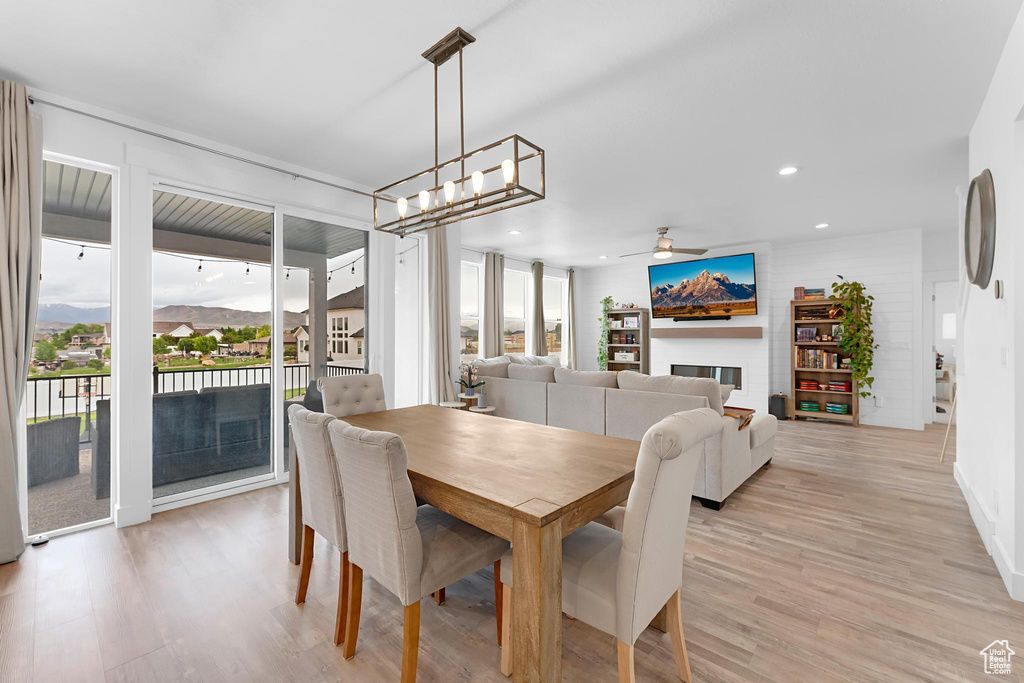 Dining area with a ceiling fan, light wood-style floors, a glass covered fireplace, and recessed lighting
