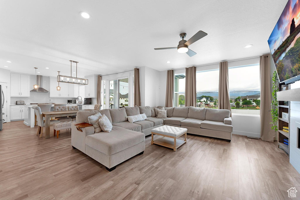 Living area with a ceiling fan, light wood finished floors, and recessed lighting