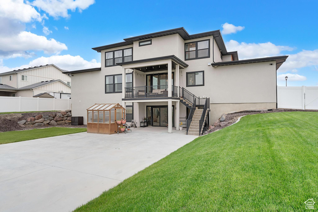 Back of house with stairway, a patio, an exterior structure, and stucco siding