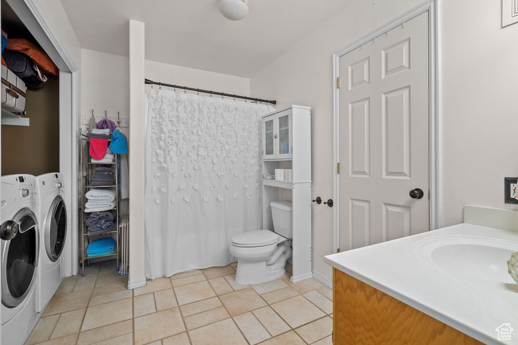 Bathroom with washer and clothes dryer, tile patterned flooring, vanity, toilet, and a shower with curtain
