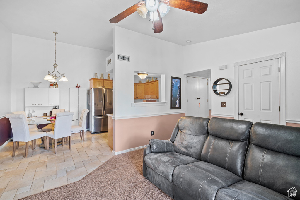 Living area with a ceiling fan, high vaulted ceiling, stone tile flooring, and baseboards