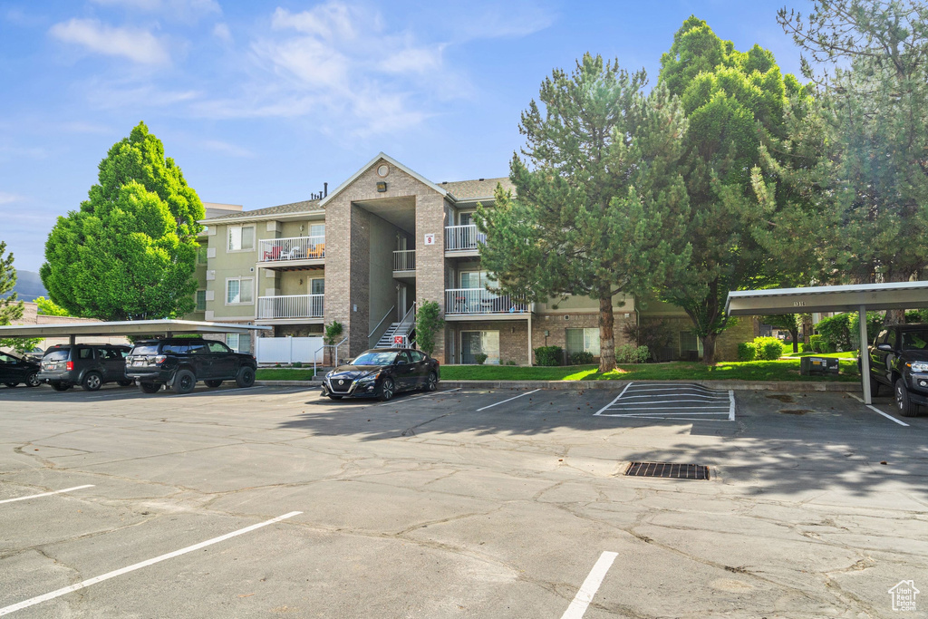 View of building exterior with covered and uncovered parking