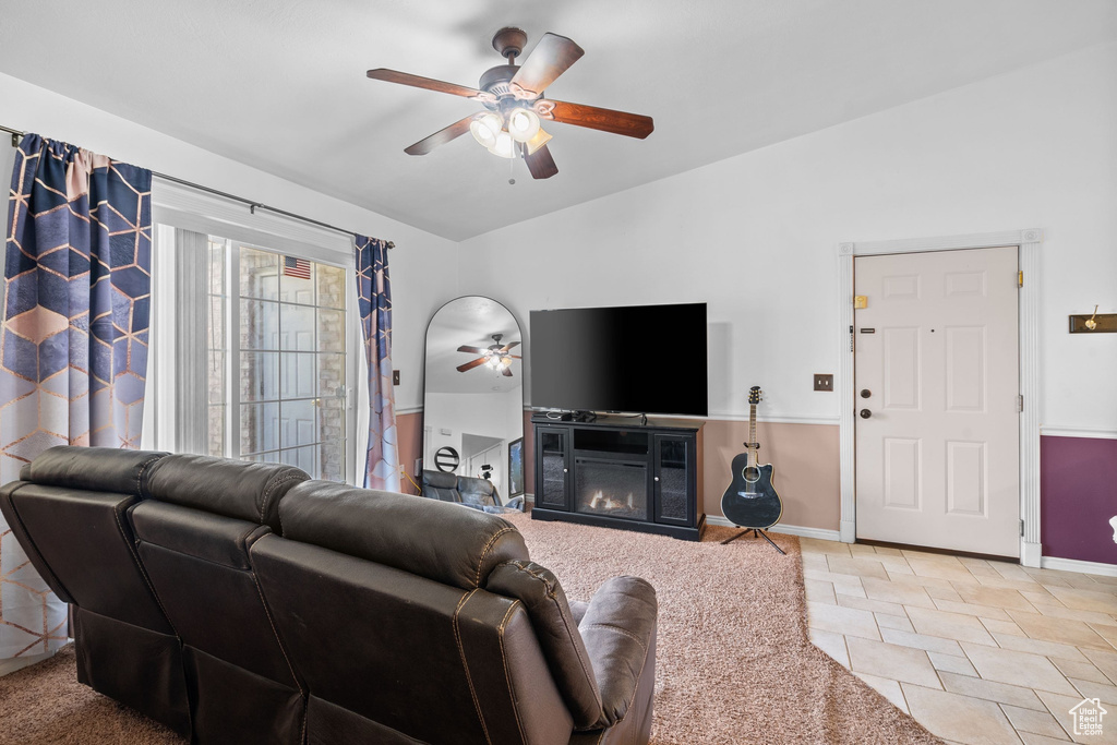 Living room featuring ceiling fan, lofted ceiling, baseboards, and a glass covered fireplace