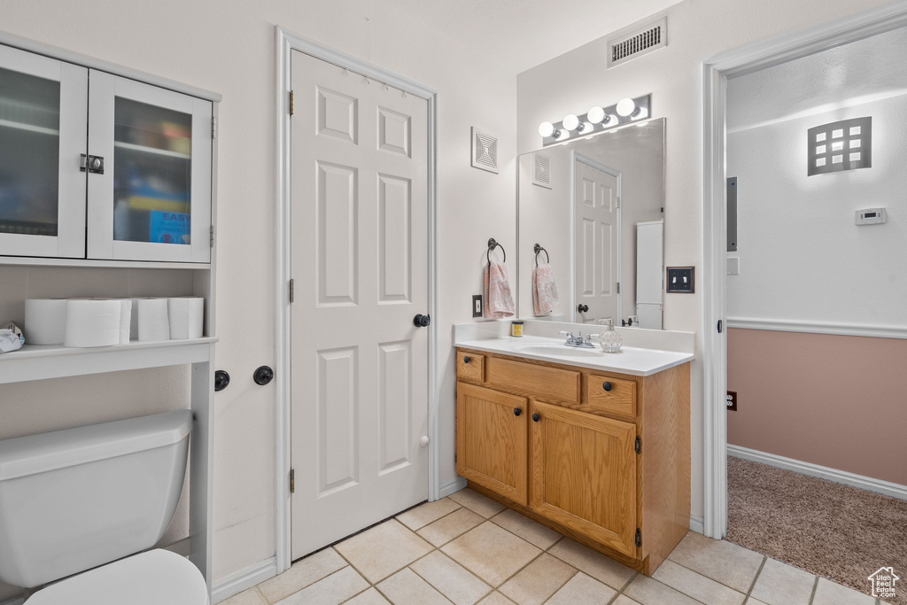 Bathroom featuring toilet, tile patterned flooring, vanity, and baseboards