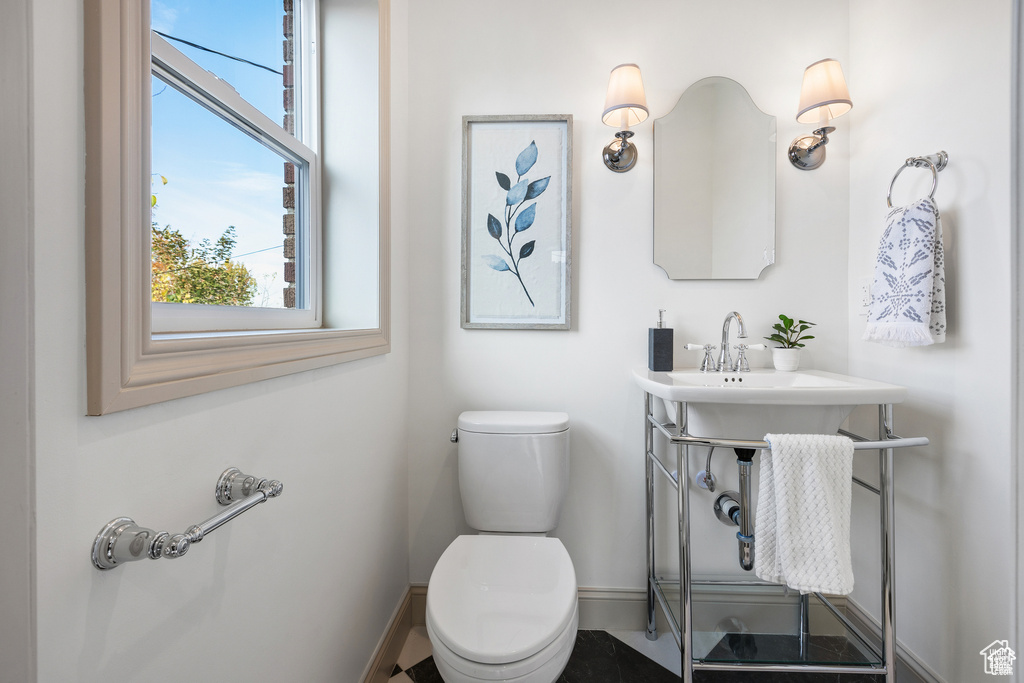 Bathroom with baseboards, plenty of natural light, and toilet