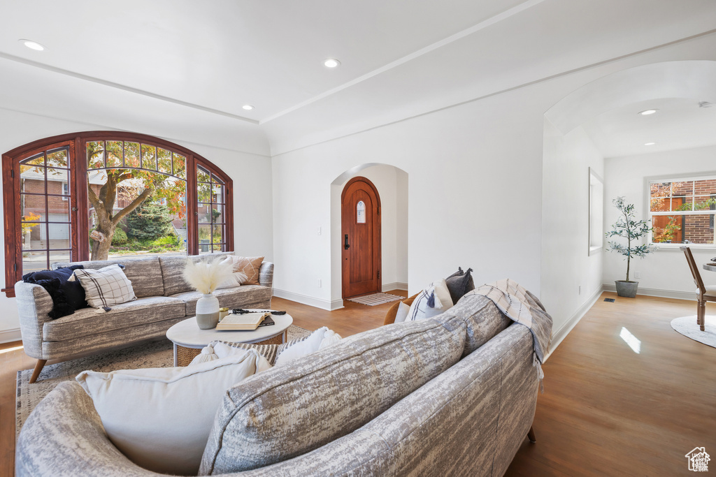 Living area featuring arched walkways, wood finished floors, baseboards, and recessed lighting