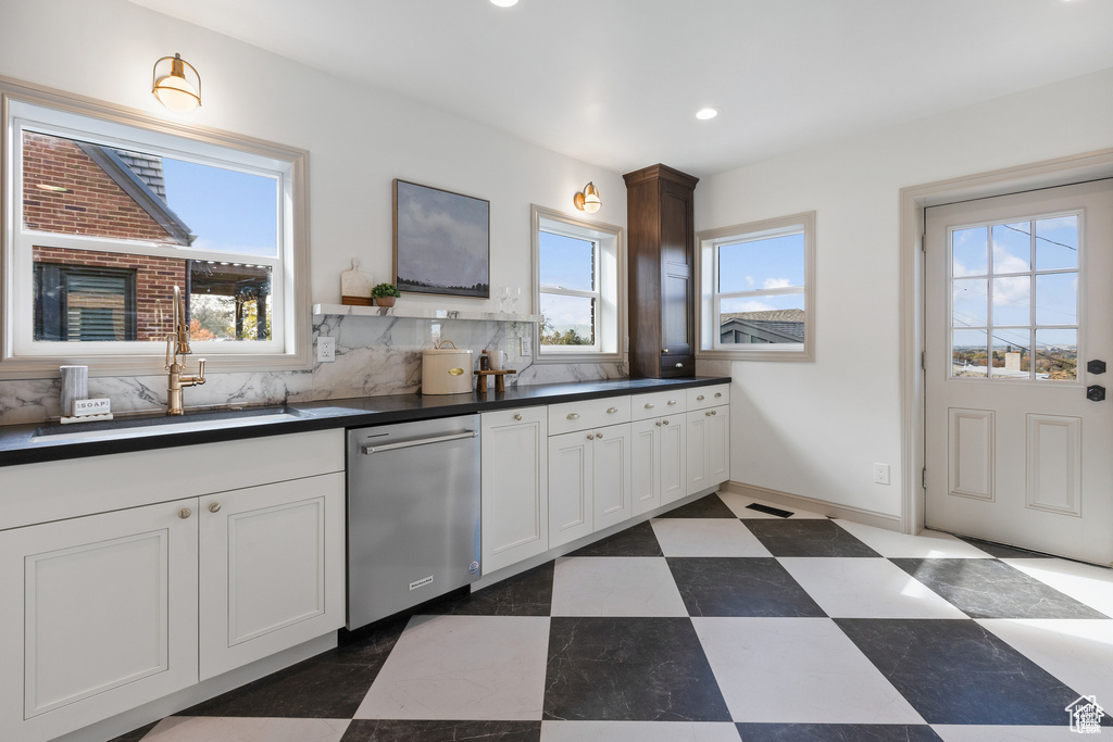 Kitchen featuring dishwasher, a sink, dark countertops, recessed lighting, and white cabinetry