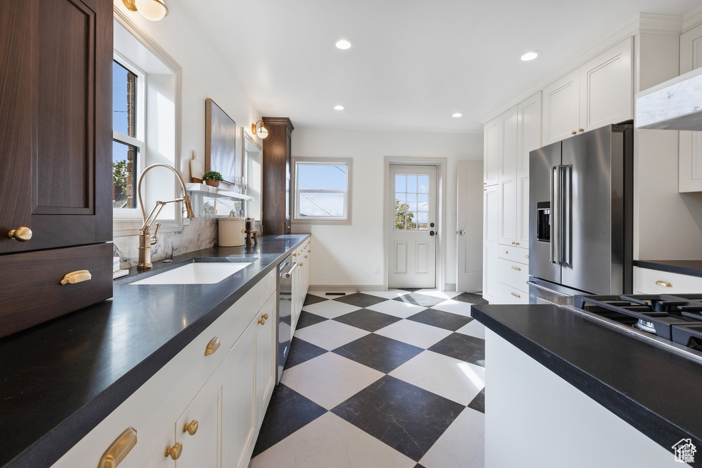 Kitchen with appliances with stainless steel finishes, a sink, dark floors, dark countertops, and recessed lighting
