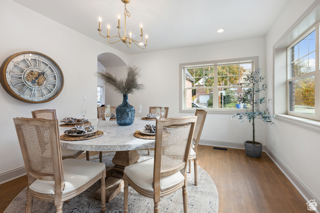 Dining area with wood finished floors, a chandelier, healthy amount of natural light, and recessed lighting