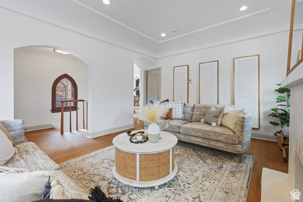 Living room with arched walkways, wood finished floors, baseboards, and recessed lighting