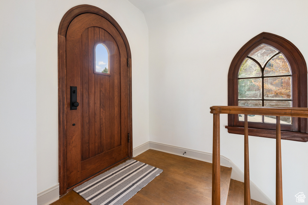 Entryway with wood finished floors, arched walkways, and baseboards