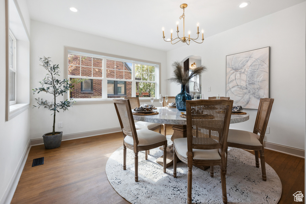 Dining space with wood finished floors, a chandelier, baseboards, and recessed lighting