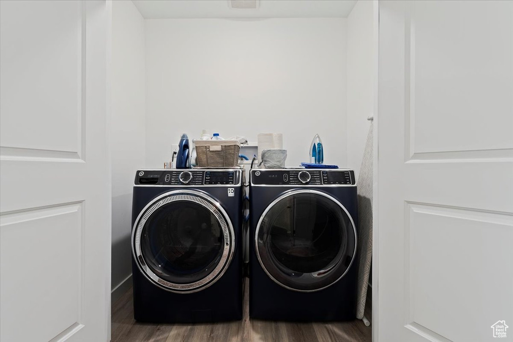 Laundry area with washer and clothes dryer and wood finished floors