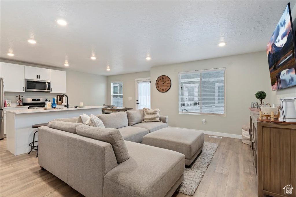 Living room with light wood-style flooring, recessed lighting, and baseboards