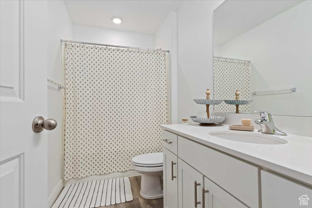 Full bath featuring toilet, vanity, wood finished floors, and a shower with curtain