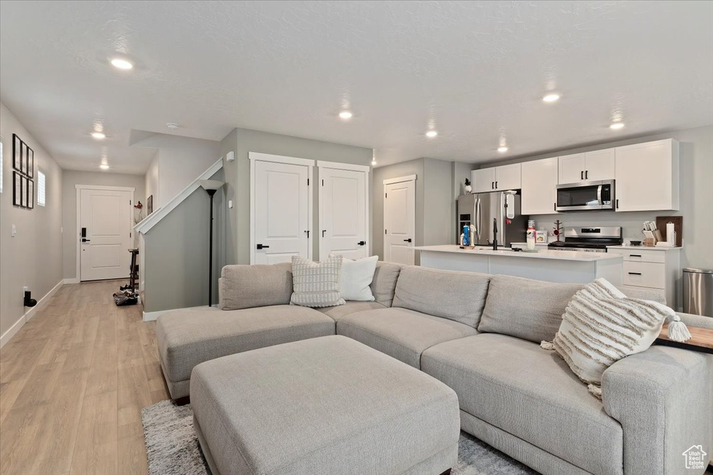 Living area with baseboards, light wood finished floors, and recessed lighting