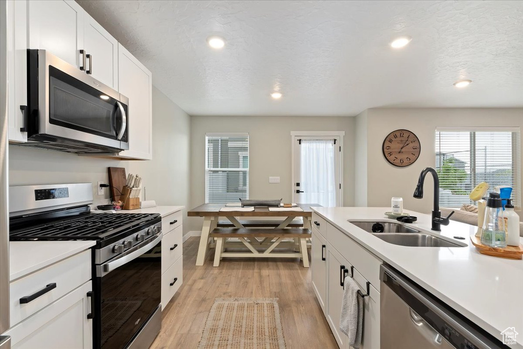 Kitchen featuring appliances with stainless steel finishes, a sink, light countertops, plenty of natural light, and recessed lighting