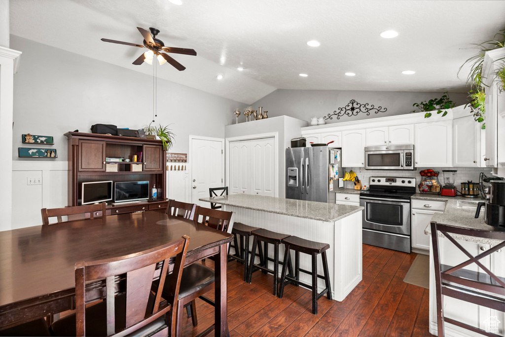 Kitchen featuring stainless steel appliances, a ceiling fan, lofted ceiling, white cabinets, and dark wood-style floors