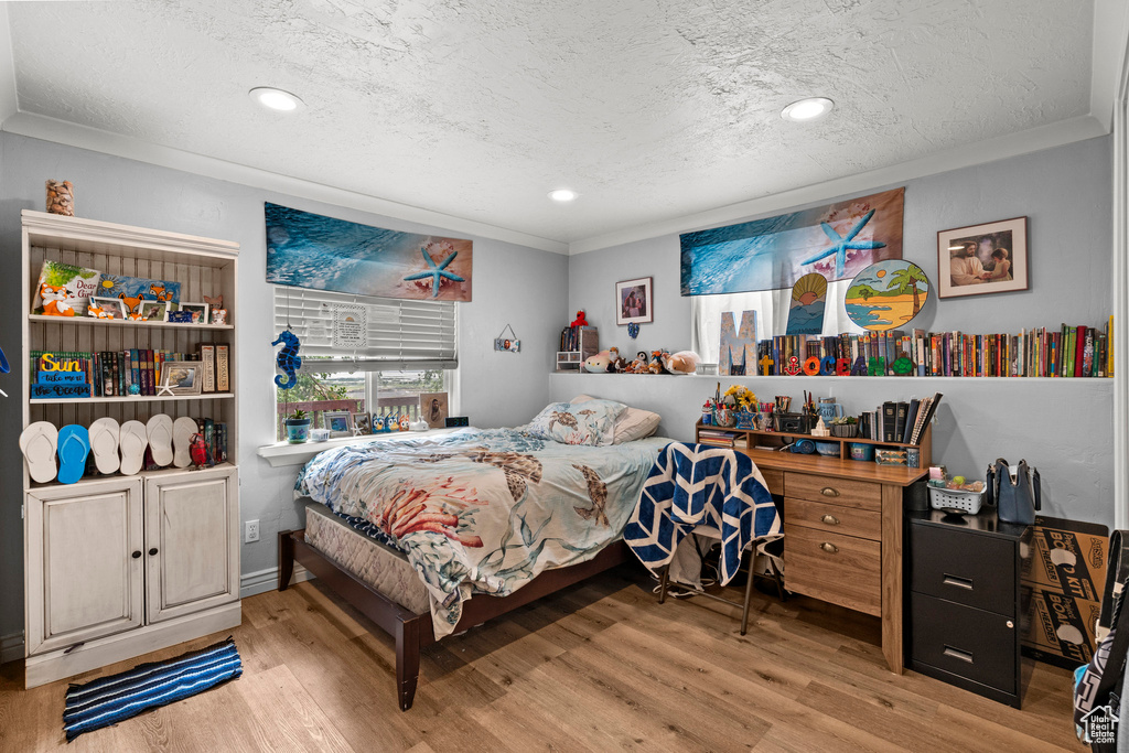 Bedroom with ornamental molding, a textured ceiling, wood finished floors, and recessed lighting