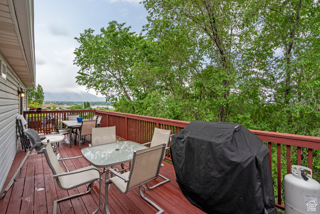 Wooden terrace featuring outdoor dining space and grilling area