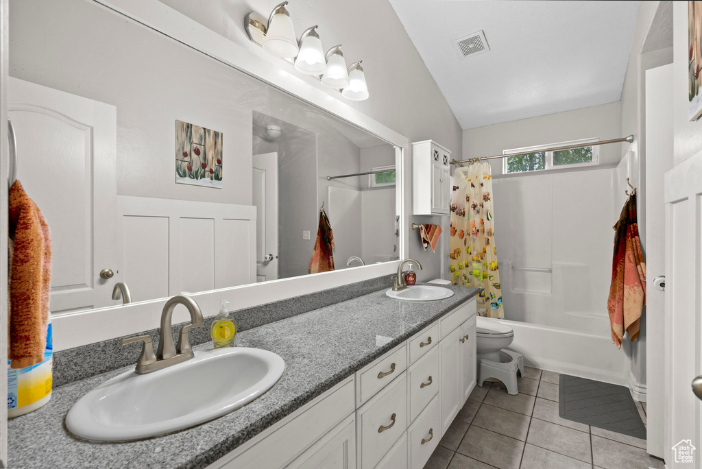 Bathroom with tile patterned flooring, shower / bath combo with shower curtain, double vanity, toilet, and lofted ceiling