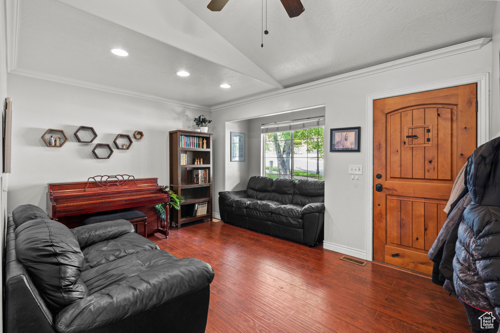 Living room with vaulted ceiling, a ceiling fan, crown molding, dark wood-type flooring, and recessed lighting