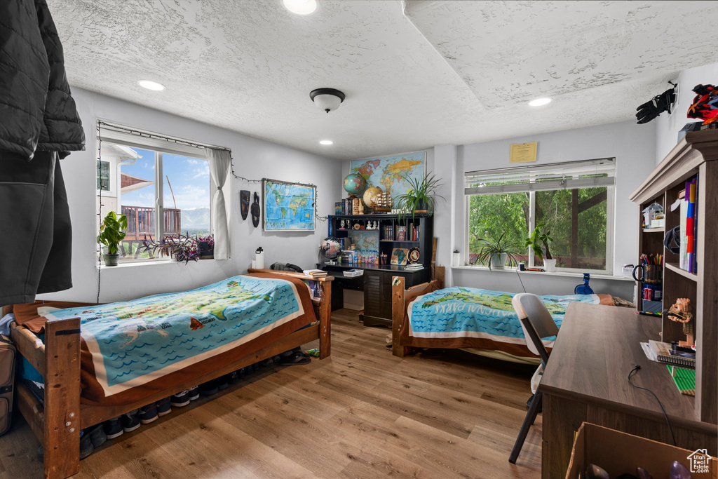 Bedroom featuring a textured ceiling, wood finished floors, multiple windows, and recessed lighting