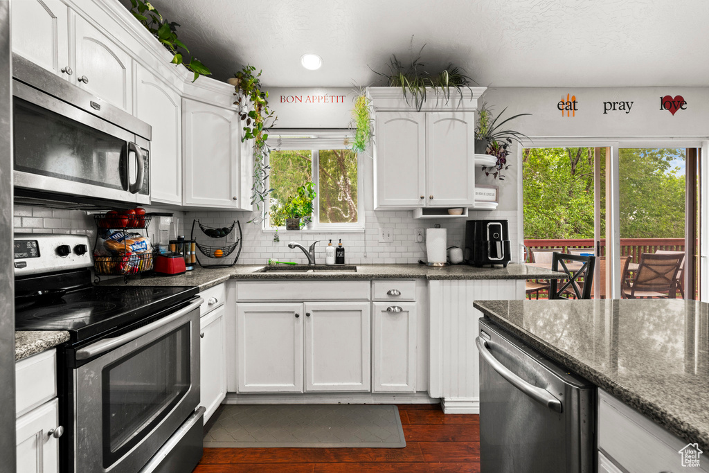 Kitchen with stainless steel appliances, a sink, plenty of natural light, white cabinets, and recessed lighting