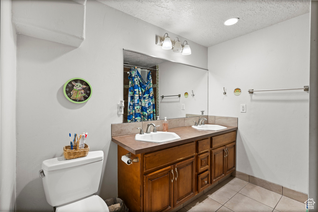 Full bath with a textured ceiling, tile patterned flooring, toilet, baseboards, and a shower with curtain