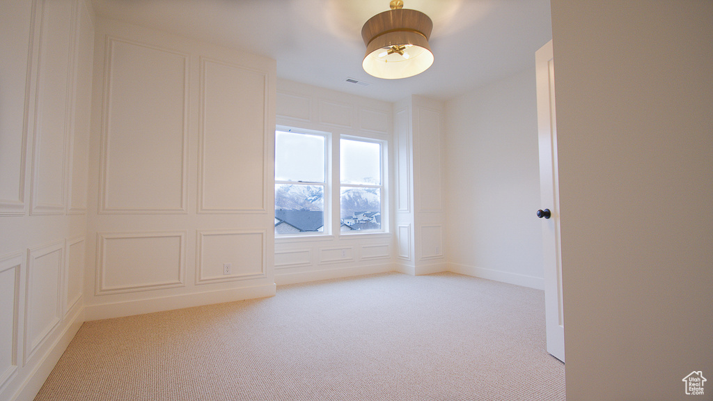 Empty room featuring light colored carpet and a decorative wall