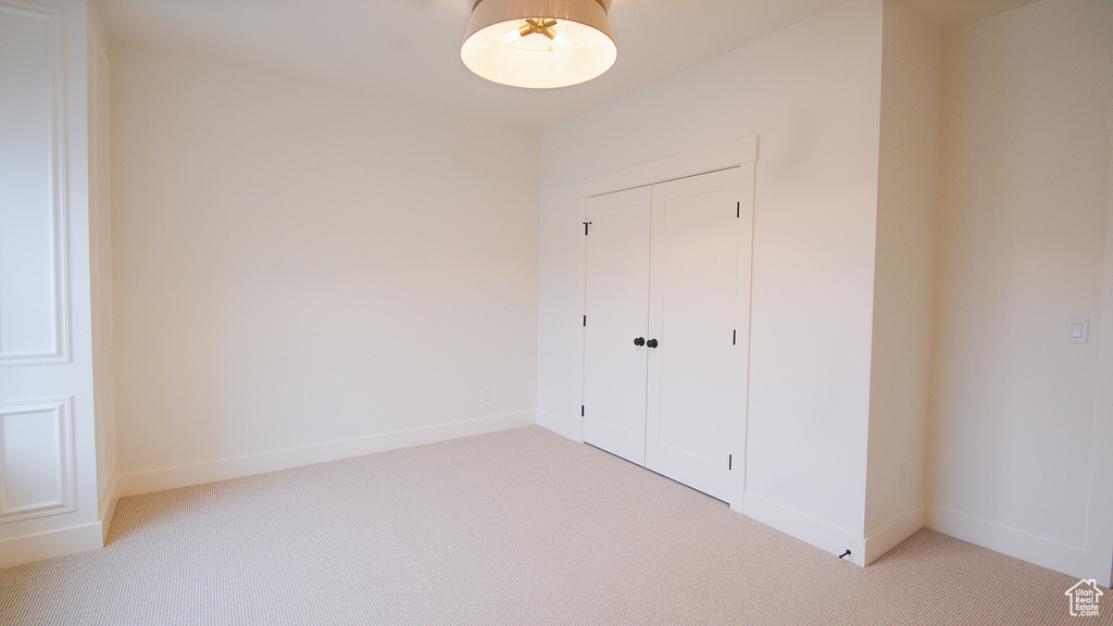 Unfurnished bedroom featuring light colored carpet, a closet, and baseboards