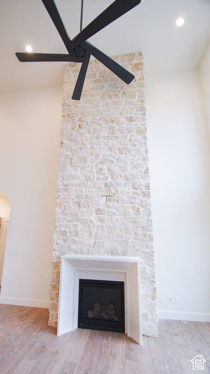 Detailed view of wood finished floors, a stone fireplace, baseboards, a ceiling fan, and recessed lighting