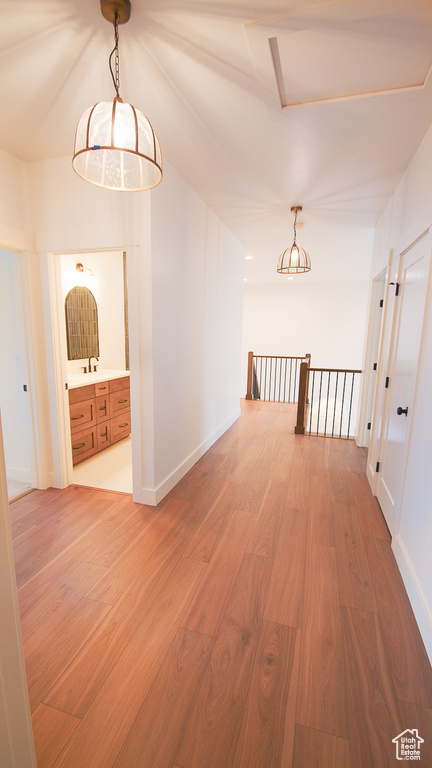 Hallway with wood finished floors, baseboards, and an upstairs landing