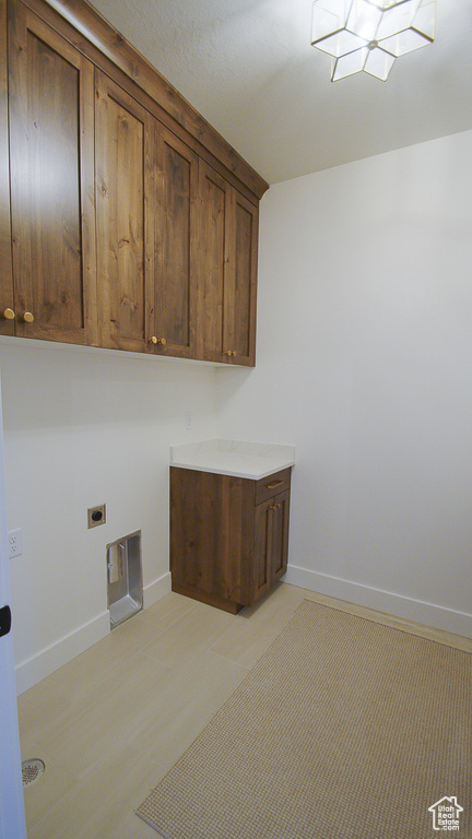 Laundry room with electric dryer hookup, cabinet space, and baseboards