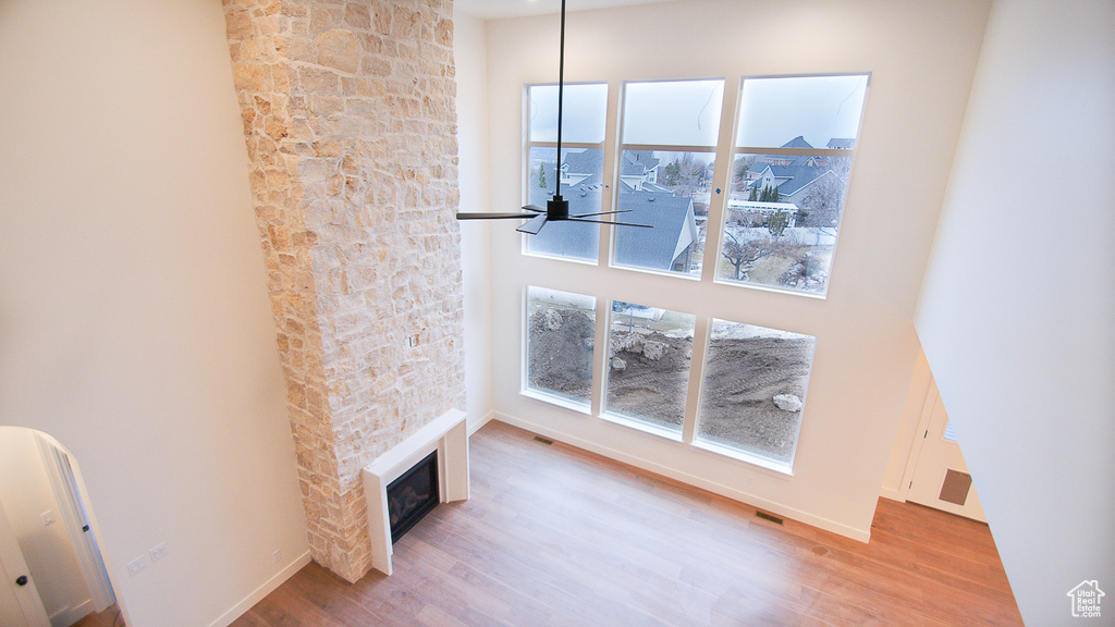 Unfurnished living room featuring wood finished floors, plenty of natural light, a glass covered fireplace, and a ceiling fan
