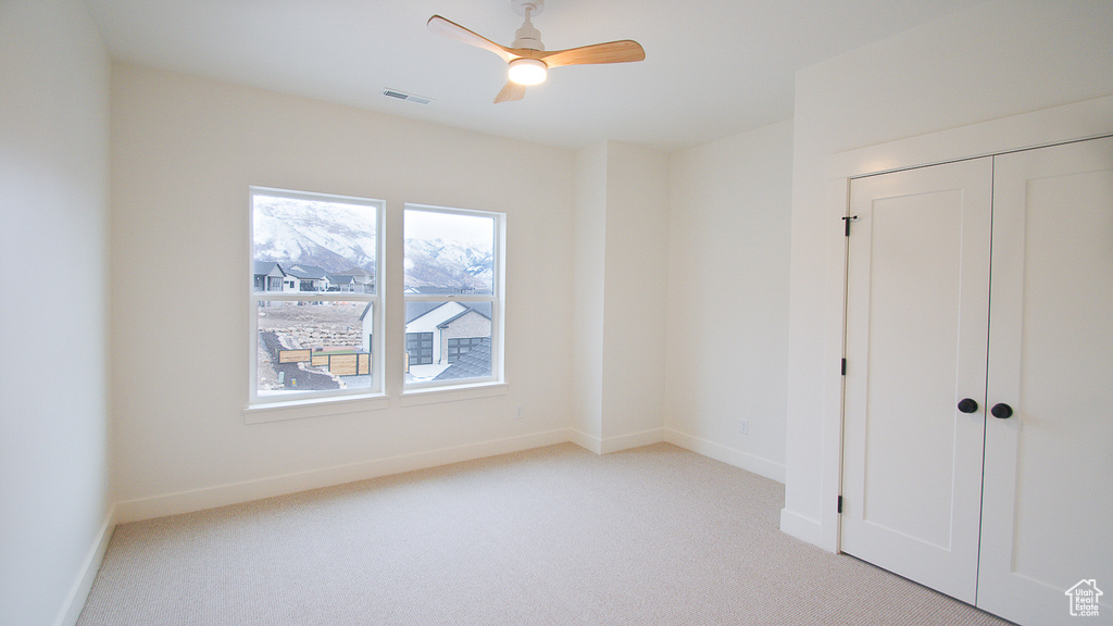 Unfurnished bedroom with carpet, baseboards, a closet, and a ceiling fan