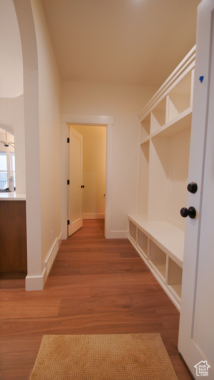 Mudroom with arched walkways, wood finished floors, and baseboards