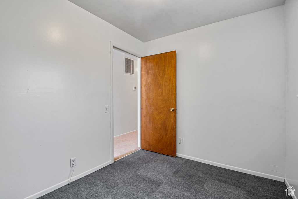 Empty room with dark colored carpet and baseboards