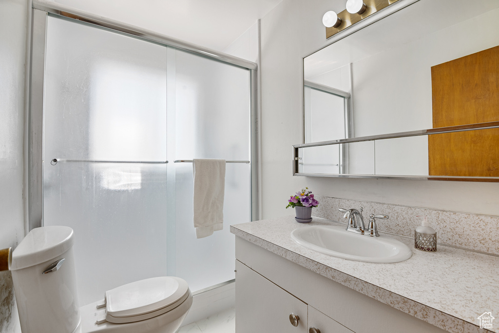 Bathroom with toilet, a stall shower, and vanity