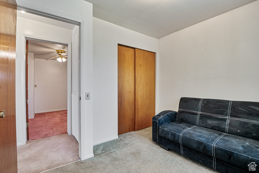 Living room with carpet floors, a ceiling fan, and baseboards