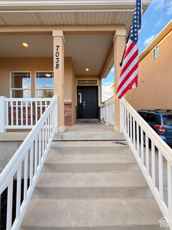 View of exterior entry with covered porch and stucco siding