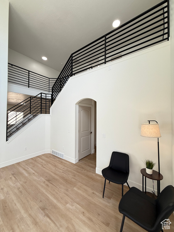Living area featuring arched walkways, baseboards, wood finished floors, recessed lighting, and a high ceiling