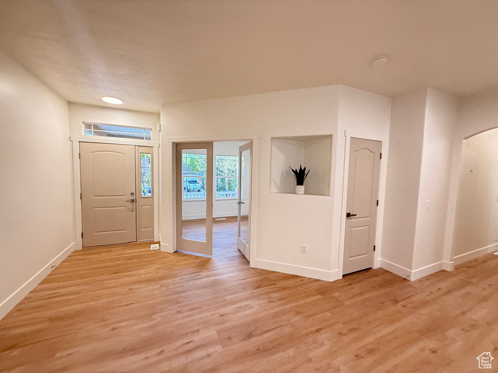 Entryway featuring baseboards, light wood-type flooring, and arched walkways