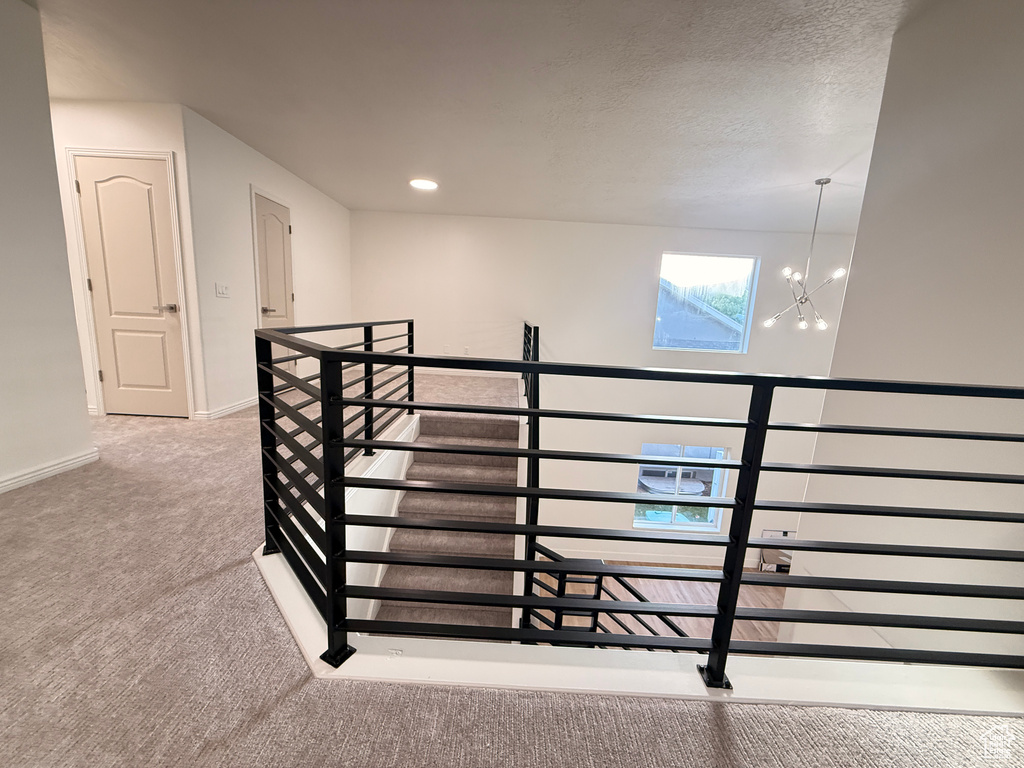 Stairway with carpet flooring, a chandelier, baseboards, and a textured ceiling