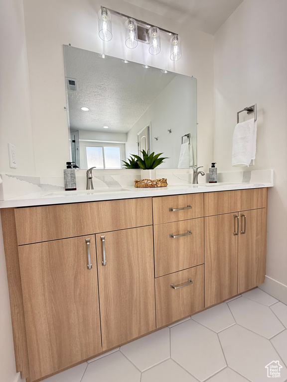 Full bathroom with double vanity and a textured ceiling