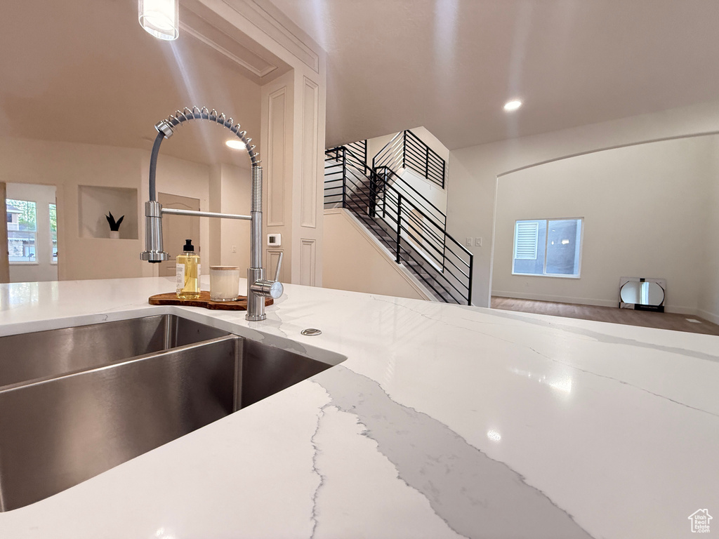 Kitchen view of a sink, light stone counters, and recessed lighting