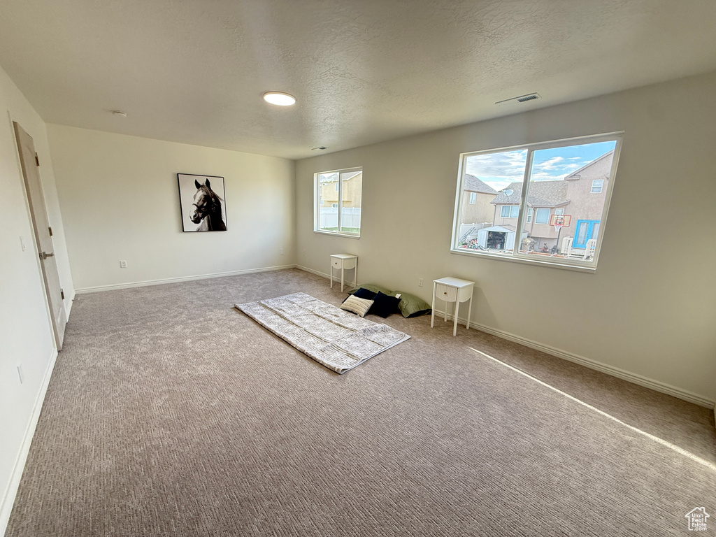Carpeted empty room with a textured ceiling and baseboards