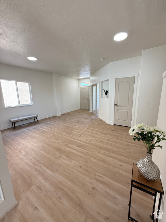 Basement with light wood finished floors, a textured ceiling, baseboards, and recessed lighting